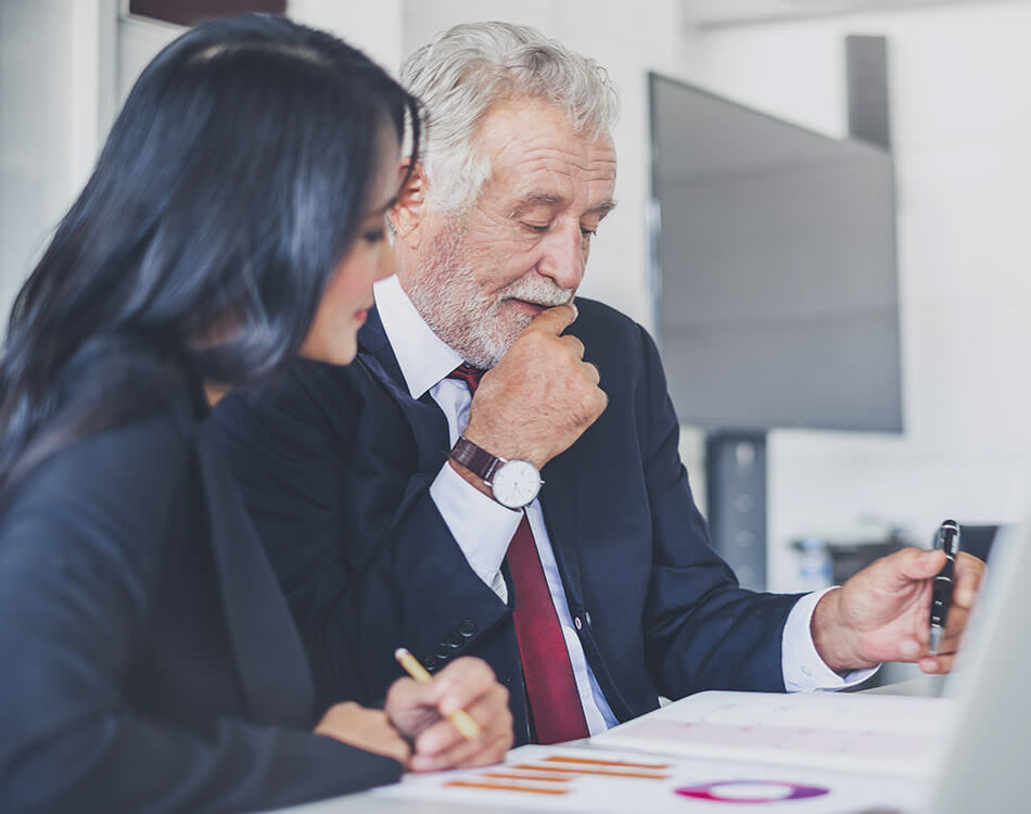 Older real estate broker coaching woman looking at statistics on paper